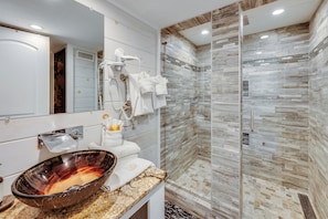 A modern bathroom with a glass-enclosed shower, a vanity with a bowl sink, and a large mirror.
