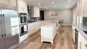 A modern kitchen with white cabinetry, stainless steel appliances, and a wooden floor. - Countryside Retreat - Come Relax, Unwind & Cast a Line (LaRue)