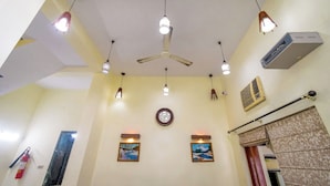 Une pièce dotée d’un ventilateur de plafond, de luminaires suspendus, d’une horloge et de deux tableaux encadrés accrochés au mur.