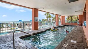 An indoor swimming pool with a view of the beach, a lifeguard stand, and a sign indicating no diving.