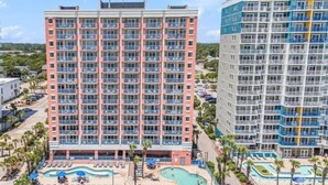 A multi-story hotel with a pool area featuring sun loungers and a small pool.