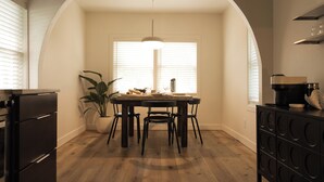 Un área de comedor con una mesa, sillas, una planta en maceta y una máquina de café.
