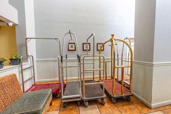 A hallway with a series of metal carts, a bench, and framed pictures on the wall.