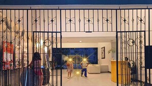 Une entrée sécurisée donnant sur un espace intérieur moderne, comprenant un comptoir d’accueil, un espace détente et des éléments décoratifs.