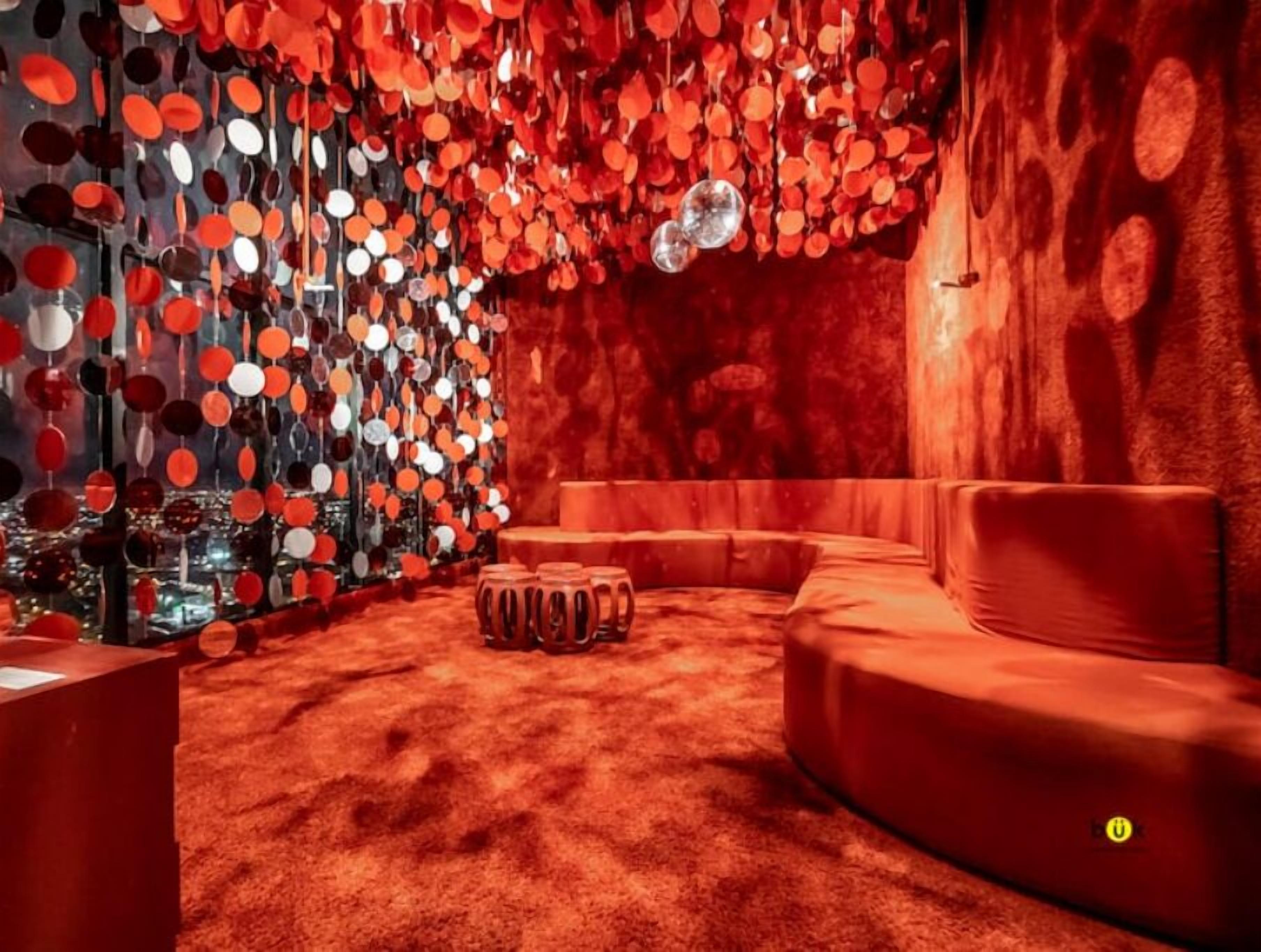 A room with a red carpet, a sofa, and a wall decorated with circular mirrors.