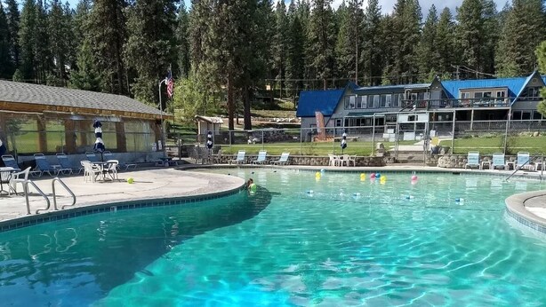 Une piscine aux eaux cristallines, avec des chaises longues, et un bâtiment avec un toit bleu en arrière-plan.