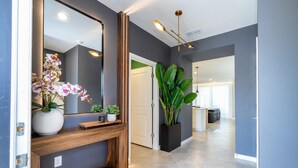 A modern hallway with a wooden console, a large mirror, and a potted plant. - 16128 - Great 5 Bedroom Home, Pool & Game Room (Clermont)