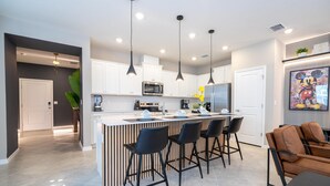 A modern kitchen with a central island, bar stools, and pendant lighting. - 16128 - Great 5 Bedroom Home, Pool & Game Room (Clermont)