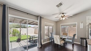 Une vaste terrasse dotée d’un espace repas, de portes-fenêtres coulissantes et d’un ventilateur de plafond.