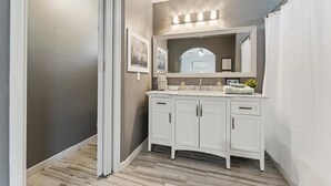 Une salle de bain avec un meuble-lavabo blanc, un grand miroir et un rideau de douche.
