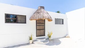 A white building with a thatched roof entrance, two potted plants, and a small set of steps leading to the door. - LAMAU-Beachfront House, San Crisanto, Yuc. (San Crisanto)