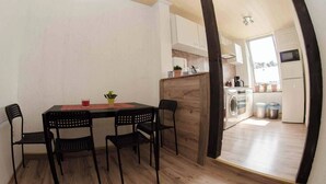 Une cuisine compacte avec un coin repas, un plancher en bois et une vue sur la pièce adjacente.
