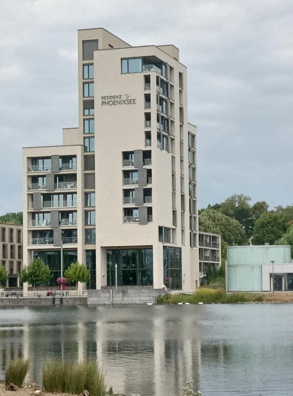 A modern multi-story building with the name "RESIDENZ PHOENIXSEE" on the facade. It features a central entrance with glass doors and multiple balconies.