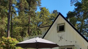 Een houten terras met buitenmeubilair, een wit huis met balkon en een reddingsboei decoratie.