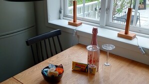 Een eettafel met een kom, een doos en een wijnglas. Op de vensterbank staan twee lampen.