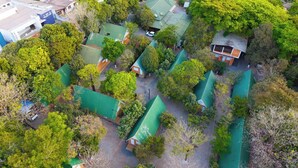 An aerial view of a residential area with multiple houses, green roofs, and surrounding trees. - HOTEL RECANTO DO BOSQUE (Sorriso)