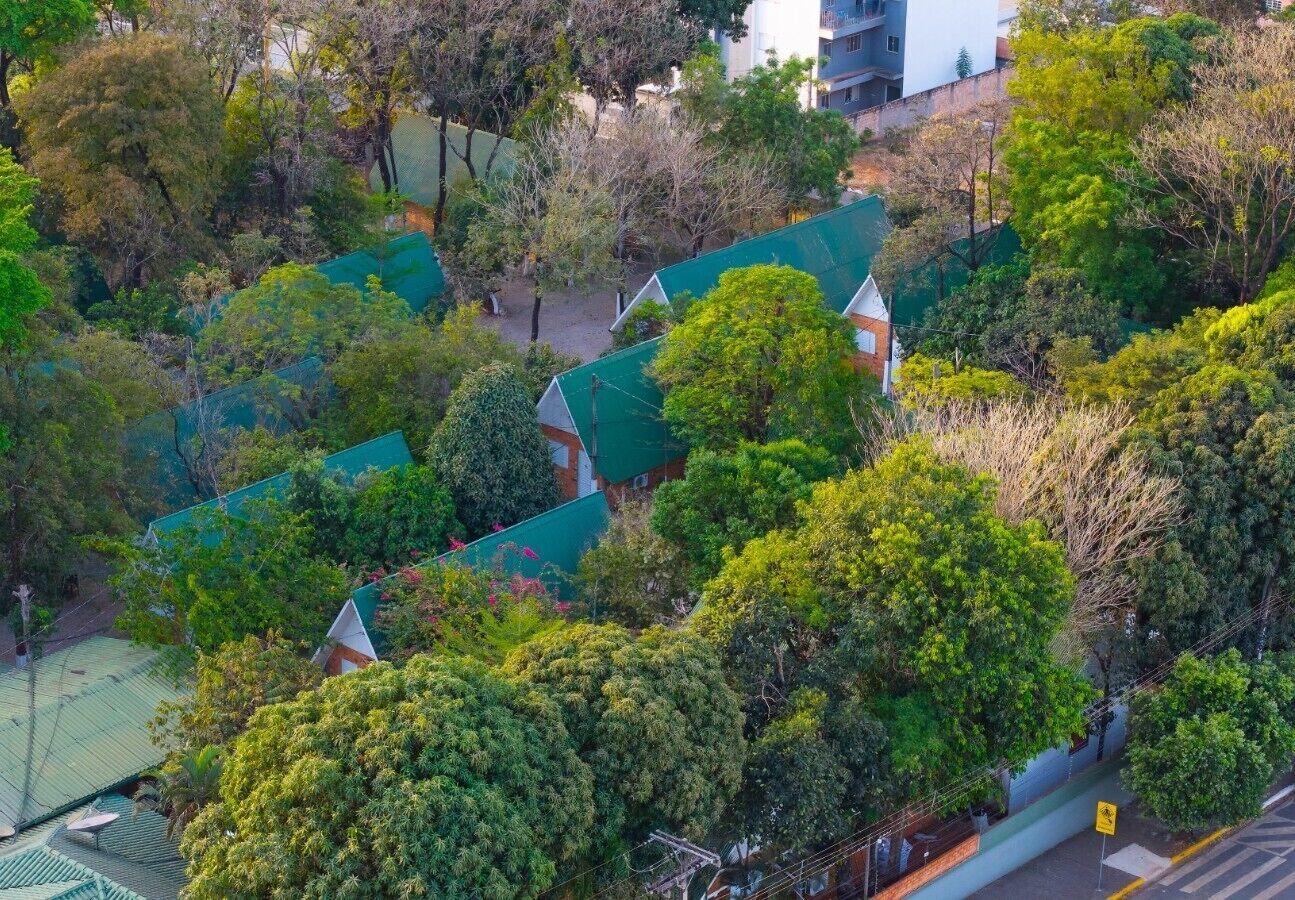 A residential area with multiple houses, each with a green roof, surrounded by dense greenery.