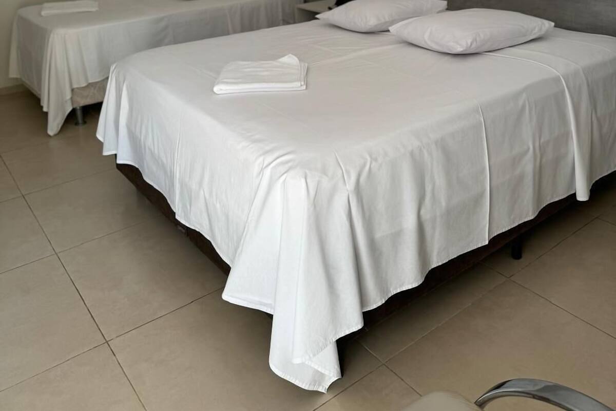 A bedroom with two single beds, a wooden headboard, and a tiled floor.