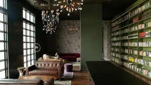 Una biblioteca con sofás de cuero, una araña y una estantería.
