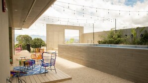 Un patio exterior con piscina, zona de estar y luces colgantes.