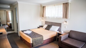 Een hotelkamer met een bed, een slaapbank, een bureau en een spiegel.