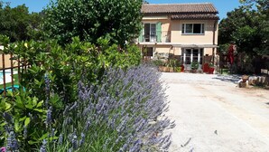A two-story house with a tiled roof, a balcony, and a garden with lavender plants. - Maison provençale Coeur du Var (first floor) (GONFARON)