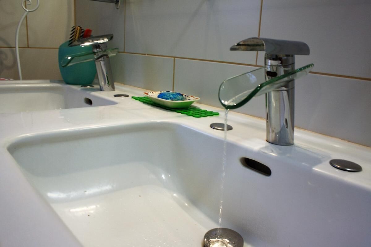 A bathroom sink with a glass bowl on the counter, a faucet, and a green soap dish.