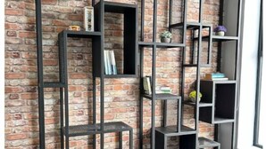 A room with a brick-patterned wall and a black metal shelving unit against it. - URBN Getaway (San Jose)