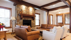 A cozy living room with a stone fireplace, leather sofas, and a patterned rug. - Spacious 4BR home in Steamboat Springs, perfect for family getaways! (Steamboat Springs)