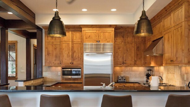 A modern kitchen with wooden cabinets, stainless steel appliances, and bar stools. - Spacious 4BR home in Steamboat Springs, perfect for family getaways! (Steamboat Springs)