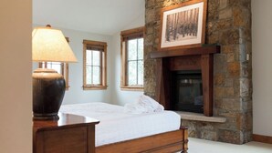 A bedroom with a stone fireplace, a bed, and a lamp. - Spacious 4BR home in Steamboat Springs, perfect for family getaways! (Steamboat Springs)