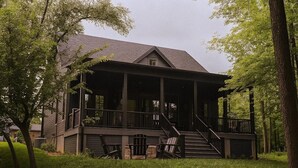 Una casa a due piani in legno, con un portico coperto e una scala che conduce al piano superiore.
