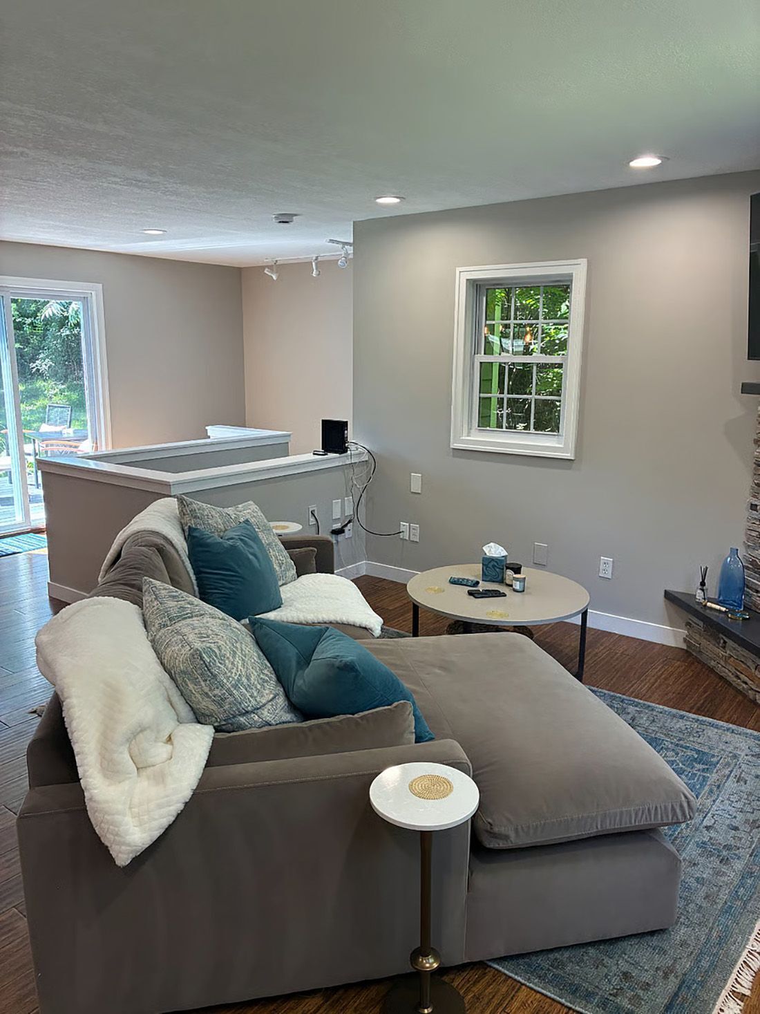 A modern living room with a grey sofa, a coffee table, and a TV mounted on the wall.