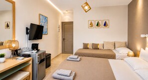 A hotel room with a bed, a desk with a computer, a TV, and a coffee machine.