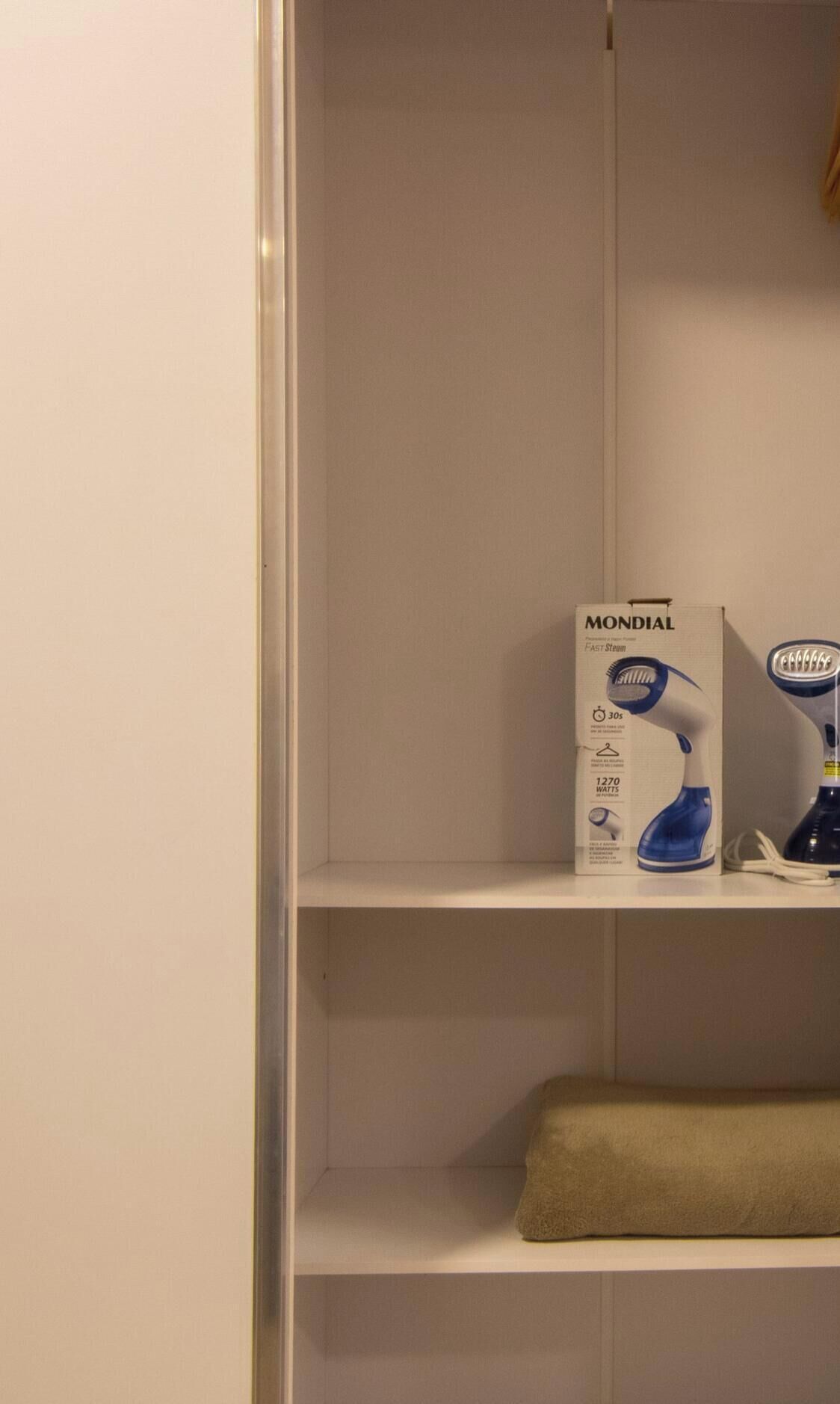Una estantería blanca con una caja etiquetada 'MONDIAL' y un secador azul.