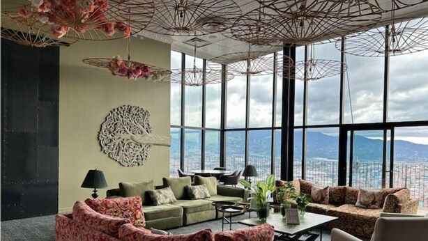 A spacious living area with a sofa set, a coffee table, and a view of the city through large windows.