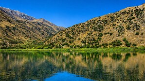 Un lac aux eaux limpides où se reflètent les paysages, entouré de montagnes et de verdure.