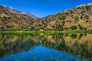 A clear lake with reflections, surrounded by mountains and greenery. - This listing contains one double room for two person. (Georgioupoli)