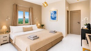 Une chambre à coucher avec un lit, des lampes de chevet, une fenêtre avec des rideaux, un tableau, une porte et une petite table sur laquelle est posée une plante.