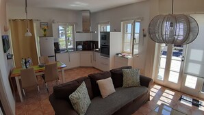 Un espacio habitable compacto con kitchenette, un sofá con cojines estampados y un comedor.