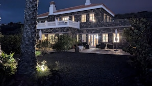 Una amplia casa de piedra con balcón, mobiliario exterior y un patio bien iluminado.