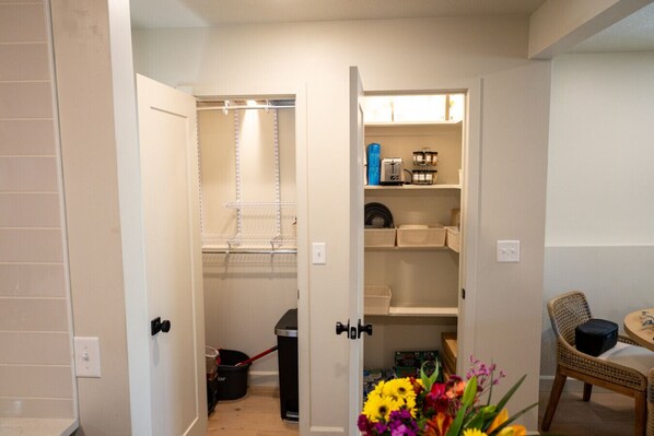 A compact storage area with shelves, baskets, and a trash bin. - The Booth Stadium Condo - Premium Tailgate Location (Lawrence)