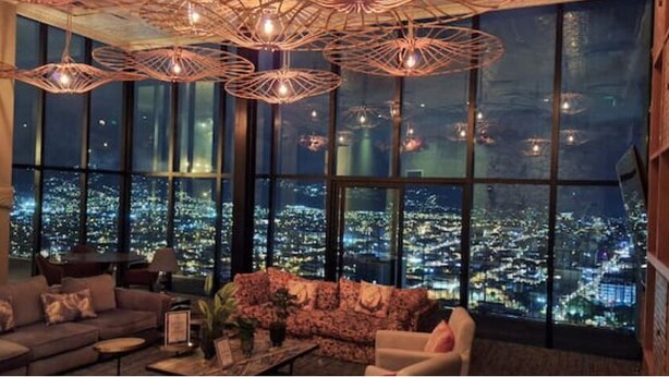 A modern living room with a city view, large windows, and contemporary furniture.