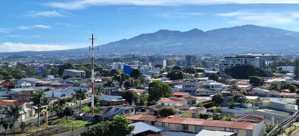 Un quartier résidentiel avec des maisons, une antenne bien visible et une montagne en arrière-plan.