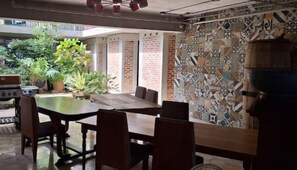 Un espace extérieur aménagé pour les repas, avec un mur en briques, un barbecue et des plantes en pot.