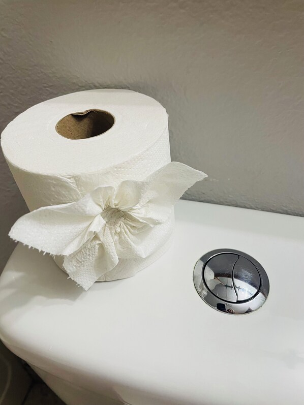 Un rouleau de papier toilette décoré d’un nœud et une lunette de toilette.
