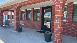 A brick building with a covered entrance, large windows, and a black door. There are two potted plants in front of the entrance. - Lincoln Hotel - King Deluxe (Lincoln)
