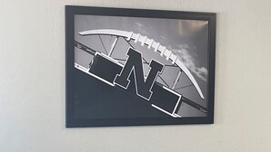 A framed artwork of a bridge on a wall, a round table with chairs, and a small potted plant. - Lincoln Hotel - King Deluxe (Lincoln)
