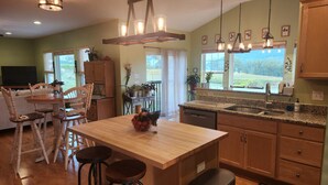 A kitchen with wooden cabinets, a granite countertop, and a central island with stools. - Mount Nittany View - Your Penn State Home for Every Big Weekend! (Boalsburg)