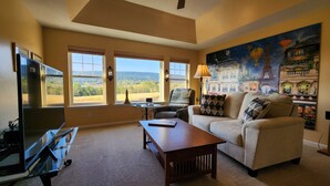 A living room with a sofa, a coffee table, a TV, and a painting of Paris. - Mount Nittany View - Your Penn State Home for Every Big Weekend! (Boalsburg)